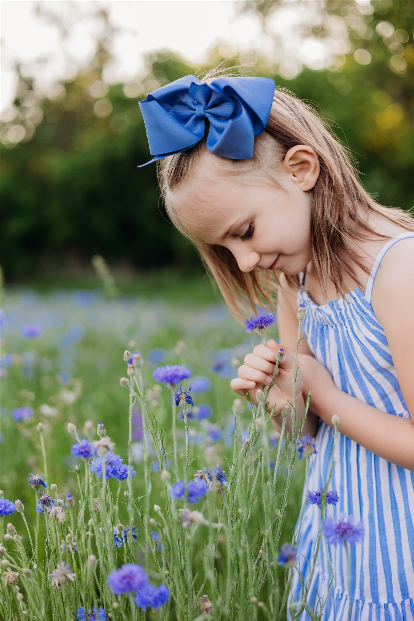 little girl in blue dress smelling flowers in a field Dallas Pediatricians
