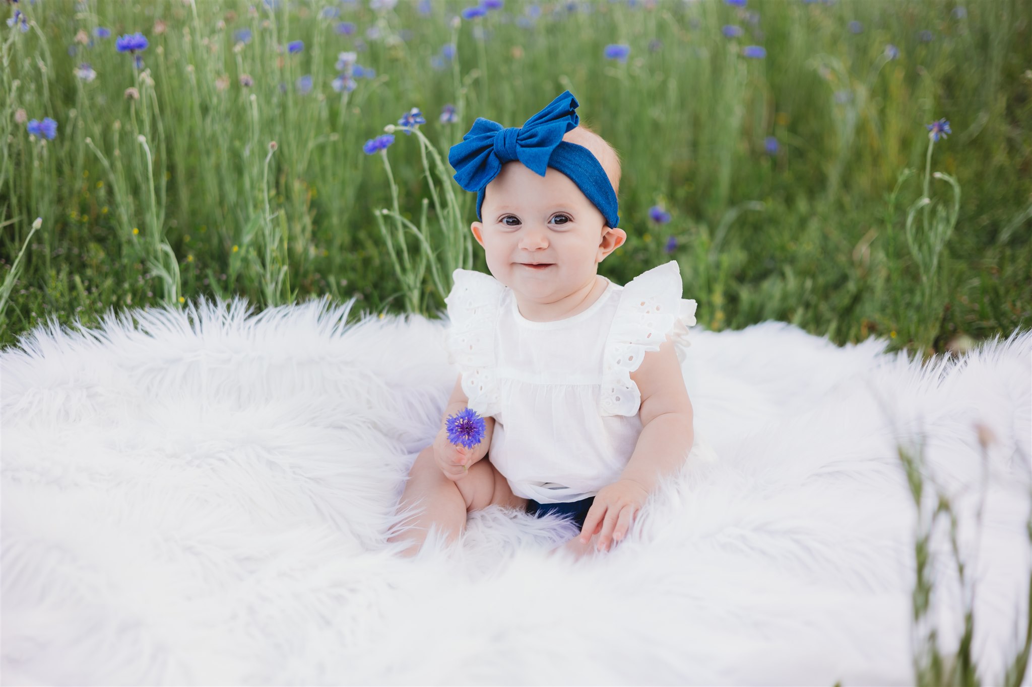 baby girl sitting on a white blanket in a field Dallas Pediatricians